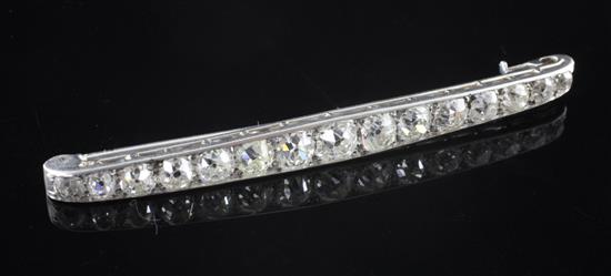 A 1920s white gold and diamond curved bar brooch, 66mm.